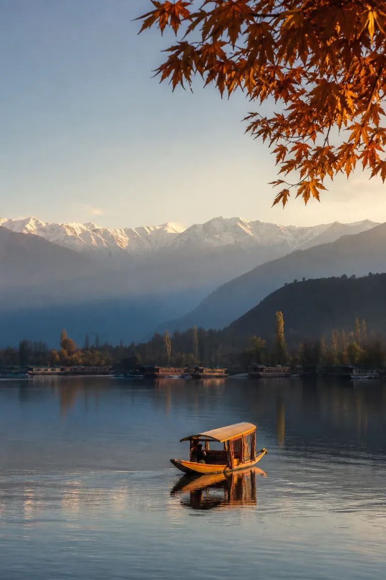 A shikara on Dal Lake beneath the snow-covered mountains of Kashmir